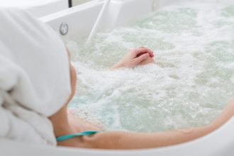 partial view of woman in with towel on head relaxing in bath in spa salon